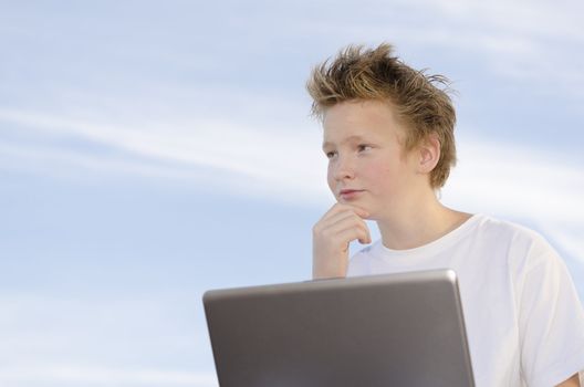 Serious schoolboy with mobile computer think about something on nature