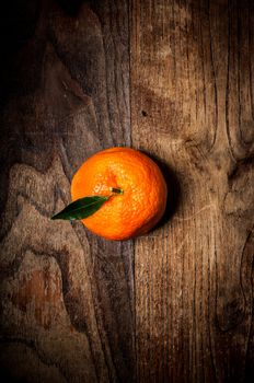 mandarin with leaf on brown wood