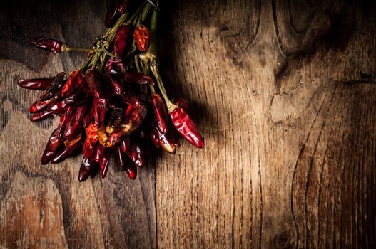 dried hot red chilies on brown textured wood