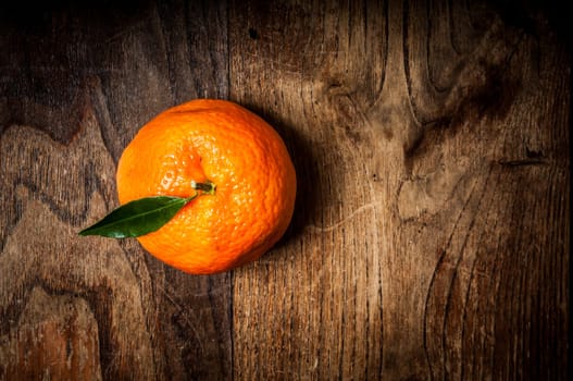 mandarin with leaf on brown wood