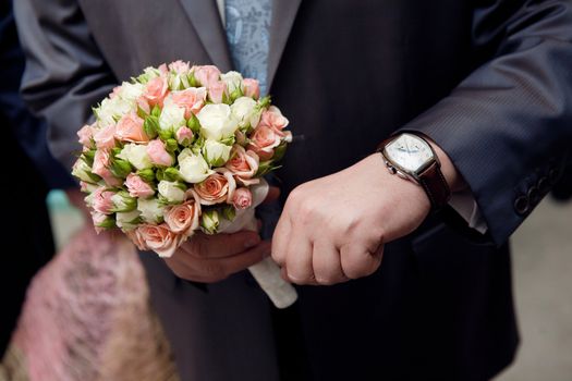 a man in suit with watch hands a flower bouquet