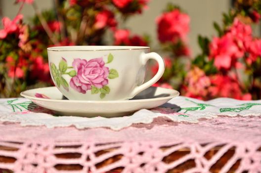 A floral pattern, antique cup with saucer in a quaint garden setting