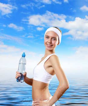 Young pretty woman in sport wear holding a bottle with pure water