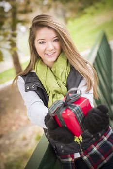 Pretty Festive Smiling Woman with Wrapped Gift with Bow Outside.