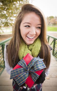 Pretty Festive Smiling Woman with Wrapped Gift with Bow Outside.