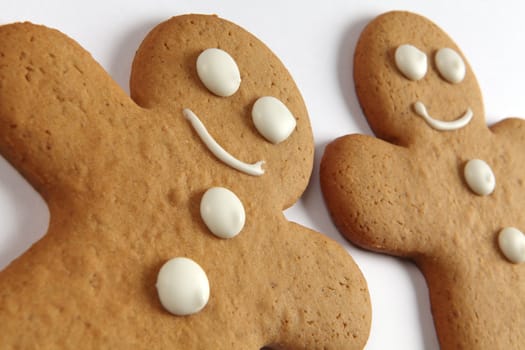 Closeup photo of two baked gingerbread man cookies on a white background.
