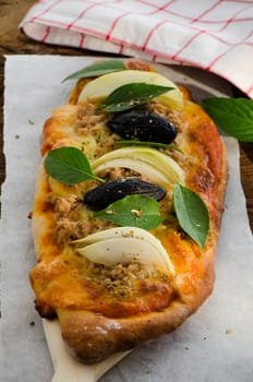 Mini homemade pizza with tuna cheese olive onion and basil on wood plate