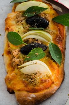 Mini homemade pizza with tuna cheese olive onion and basil on wood plate