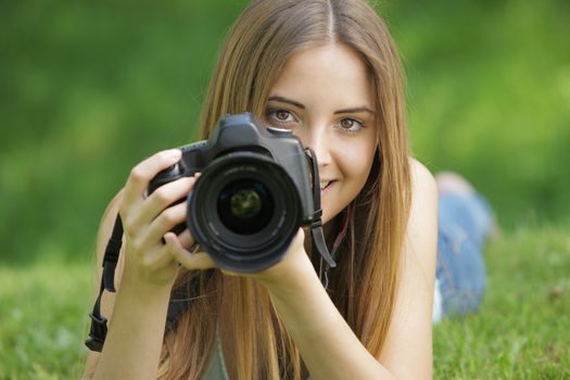 Portrait of beautiful smiling blonde girl , making photos at summer green park.