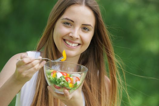 Portrait of young happy woman eating salad