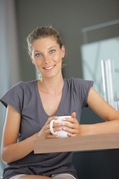 Beautiful girl in kitchen with a cup of cofee or tea