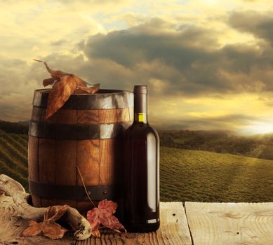 red wine bottle and wodden barrel, vineyard on background