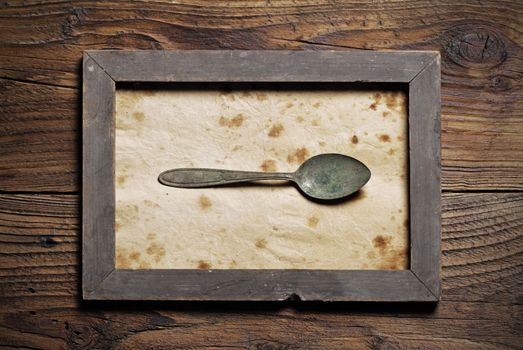 Metal spoon framed on old wood background
