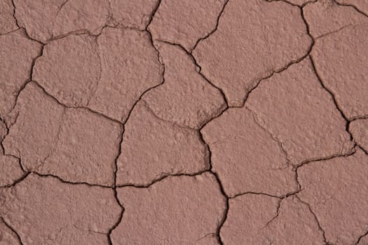 A dried patch of red clay earth with cracks making a mosaic pattern