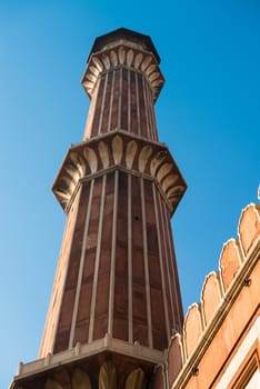 High minaret in Jama Masjid Mosque, Dehli, India with blue sky on background