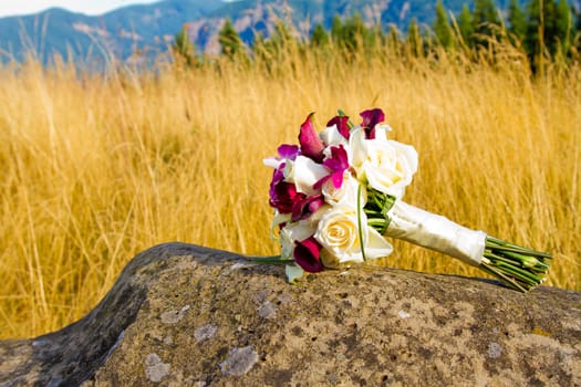 The bouquet of a bride has been laid down away from the ceremony and reception on her wedding day. The flowers in the bouquet are beautiful.