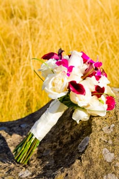 The bouquet of a bride has been laid down away from the ceremony and reception on her wedding day. The flowers in the bouquet are beautiful.