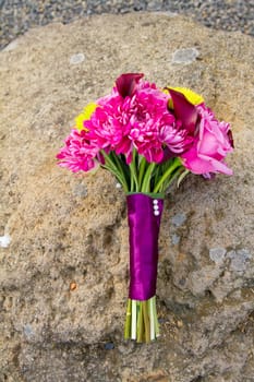 The bouquet of a bride has been laid down away from the ceremony and reception on her wedding day. The flowers in the bouquet are beautiful.