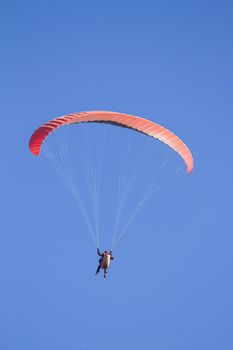 A paraglider takes to the sky. Shot from below against a blue sky.