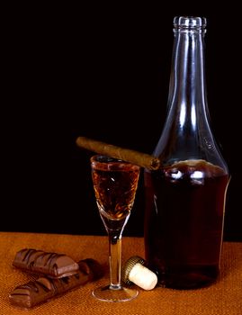 A bottle of brandy and cognac glass crystal, chocolate and cigar
