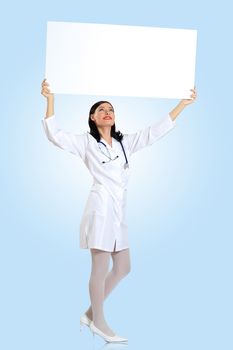 Portrait of happy successful young female doctor holding blank banner