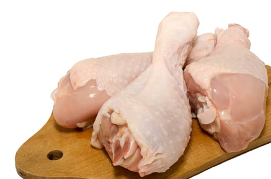 Raw chicken drumsticks lined up on a cutting board.