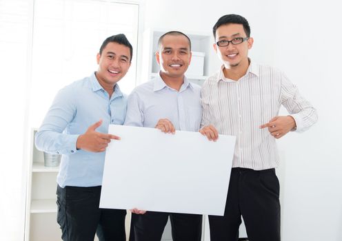Southeast Asian business team holding a blank banner in office