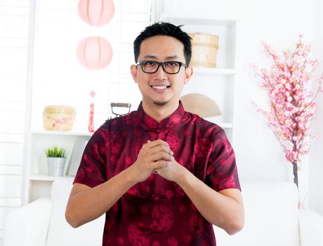 China man in traditional Chinese Tang suit greeting, indoors