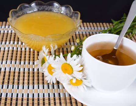 Bouquet of daisies and a cup of tea with honey on the table