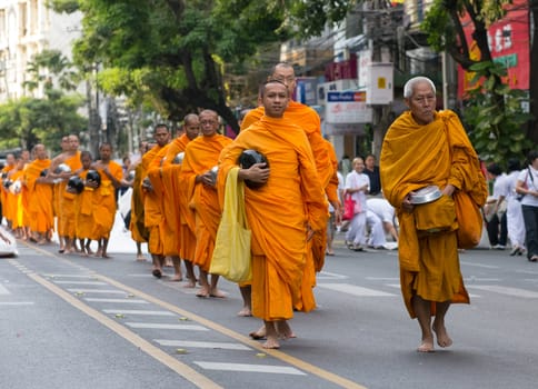 BANGKOK - DECEMBER 23: Monks participating in a mass alms giving in the morning at Soi Thonglor in celebration of the 2,600th anniversary of Lord Buddha's enlightenment on December 23, 2012 in Bangkok, Thailand.