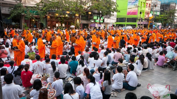 BANGKOK - DECEMBER 23: Participants at a mass alms giving in the morning at Soi Thonglor in celebration of the 2,600th anniversary of Lord Buddha's enlightenment on December 23, 2012 in Bangkok, Thailand.