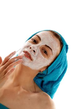 Young Women in Blue Towel on her Head Applying White Facial Skincare Mask closeup on white background
