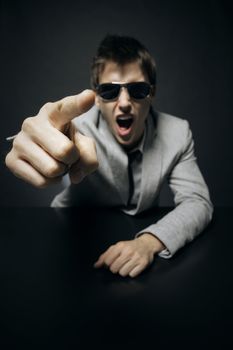 Young angry businessman boss is pointing his finger and screaming