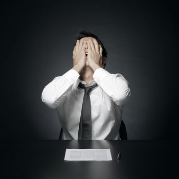 portrait of desperate office manager  covering his face with both hands