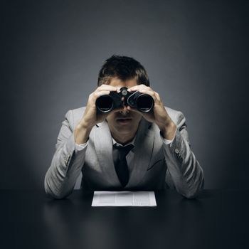 Young businessman looking through binoculars