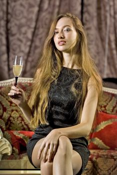 beautiful woman on a sofa with glass of brut
