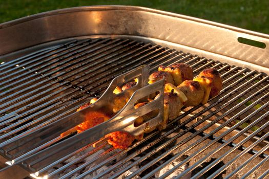 Cooking a few Meat Brochettes on a Barbecue outside in the garden