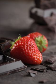 Fresh strawberries and chocolate pieces on old wood background