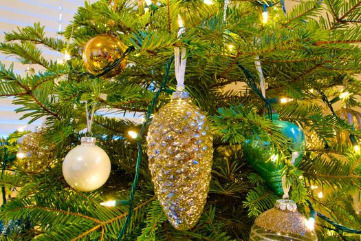 Elegant beautiful Christmas tree ornaments hang from this fir with lights and decorations all around.