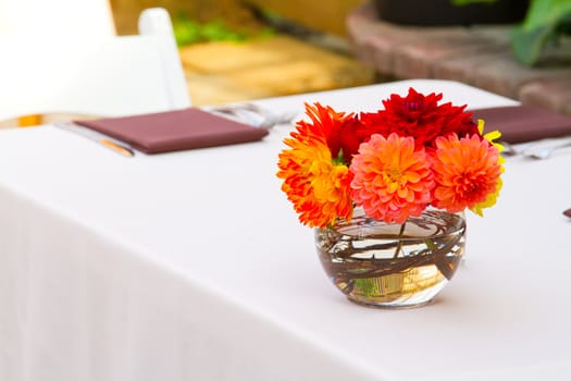 Wedding decor at a ceremony and reception with beautiful red and yellow flowers.