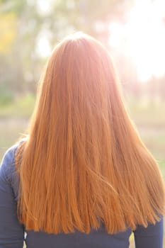 Gorgeous redhead girls hair from back. Outdoors, backlit