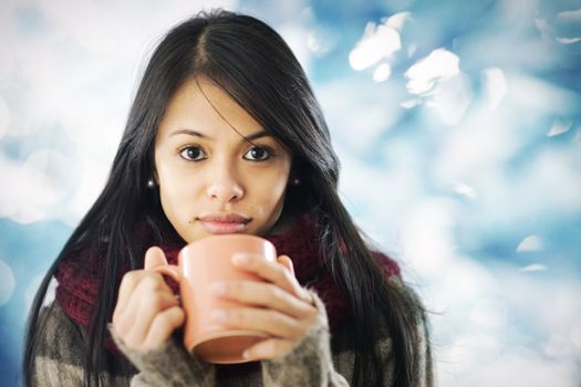Beautiful young woman in warm clothing with hot beverage