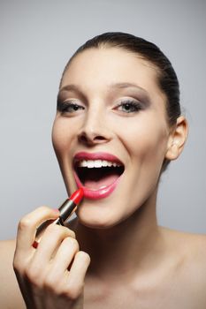 Portrait of beautiful young woman applying red lipstick