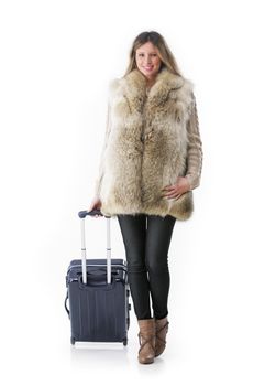 Young woman in winter clothes with a rolling suitcase.
