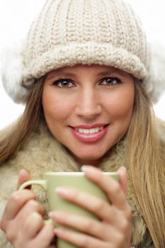 Young woman wearing winter clothes having a hot drink 