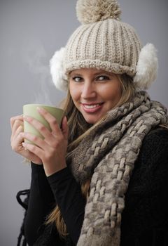 Young woman wearing winter clothes having a hot drink 