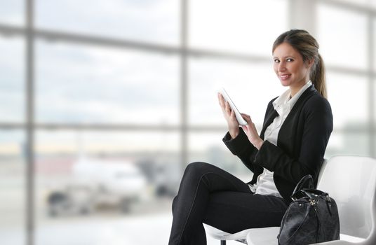 Portrait of young business woman working on digital tablet at airport