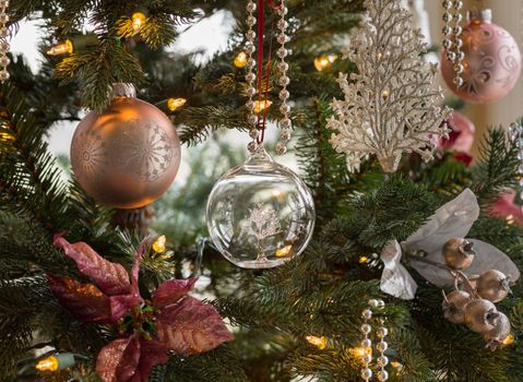 Macro shot of glass globe with tree on indoor christmas tree with decorations