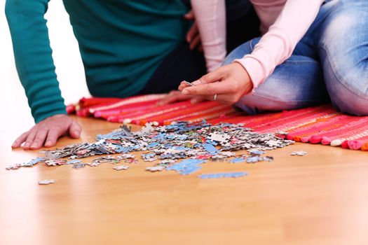 Granny and granddaughter playing puzzle on a floor