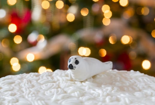 Seal on iced christmas cake with lights of xmas tree out of focus in background